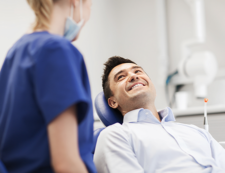 Patient smiling at dental assistant while sitting in treatment chair