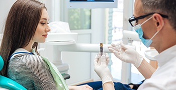 A dentist showing his patient a dental implant